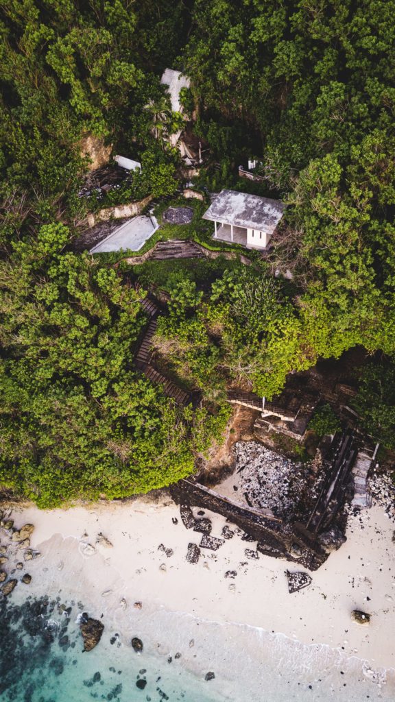 An aerial view of an abandoned tropical resort building on a cliffside