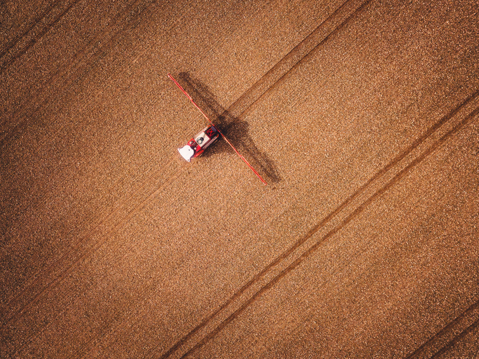 Heavy farmland machinery running through turned brown soil after the harvest