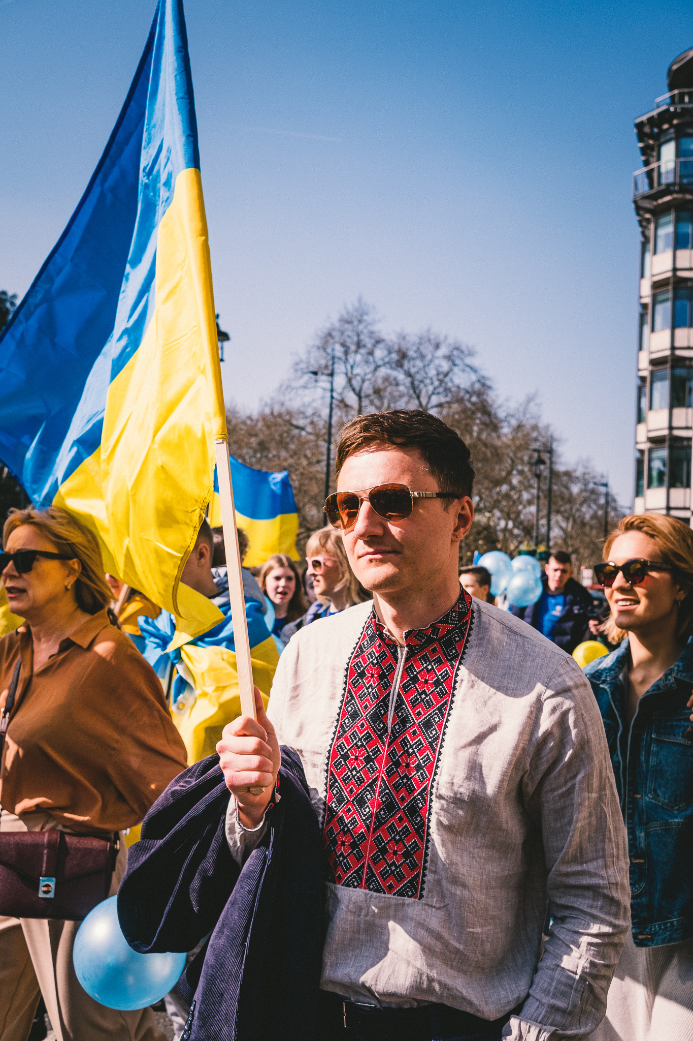 A protester wearing an ethnic motif embroidered shirt carrying a flag of Ukraine