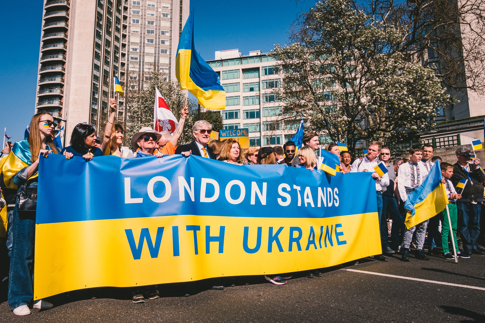 A group of protesters at the start of the march in solidarity with Ukraine holding a large banner that says: “London Stands with Ukraine”