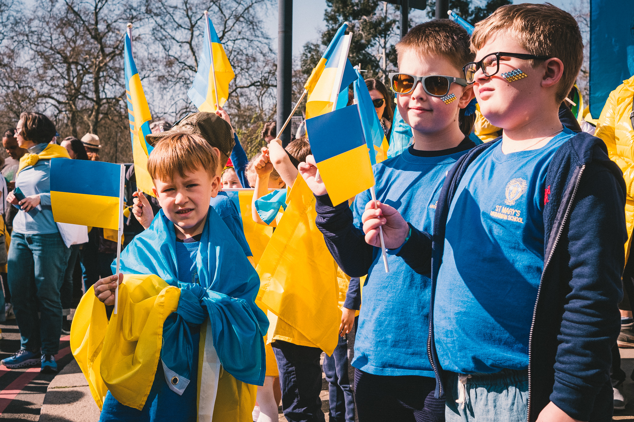 A group of boys holding Ukrainian flags before the solidarity march begins