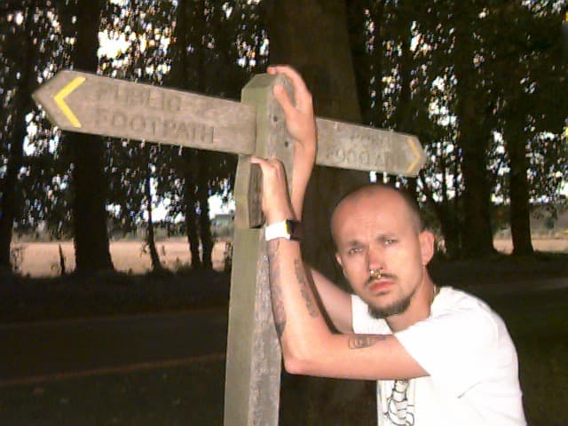 Young man posing next to a Public Footpath sign