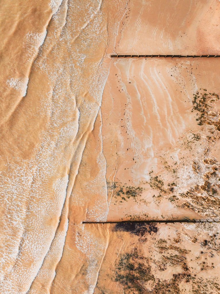 Top down view of two wooden coast erosion walls on a sandy beach