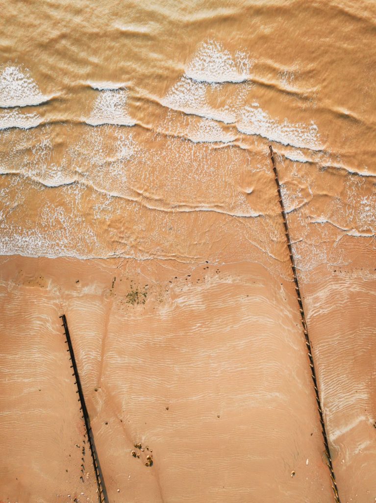 Top down view of two wooden coast erosion walls on a sandy beach