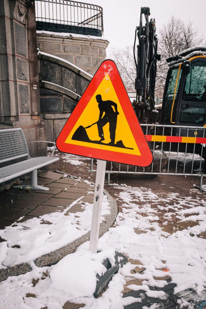 A street sign notifying pedestrians of a construction ahead on a snowy street of Örnsköldsvik